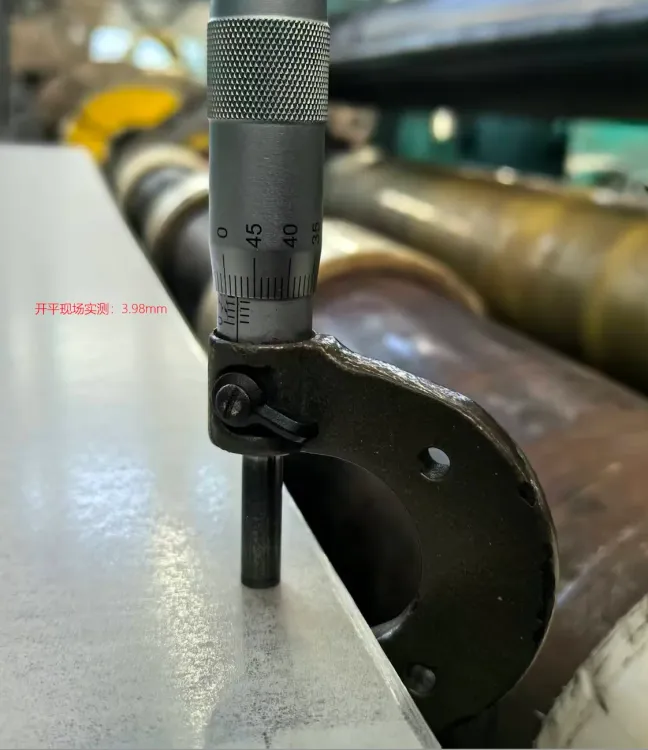 Micrometer measuring hot-rolled stainless steel sheet thickness on the leveling line, reading 3.98 mm within the ±0.05 mm tolerance target