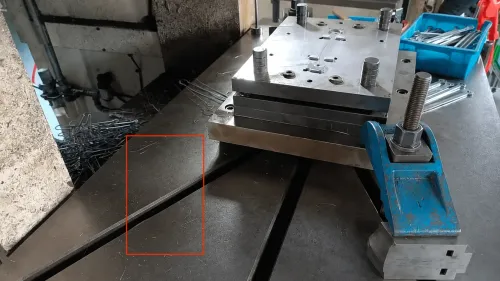 Stamping die set on the press table with burr slivers scattered around stamped stainless steel parts