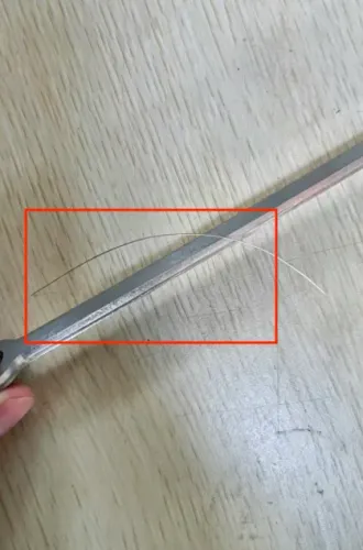 Wire-edge burr on a stamped 304 stainless steel turbocharger vent valve connecting plate, highlighted in red
